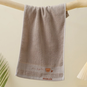 Detail of soft cotton kids towel in light brown with cute bear embroidery and texture