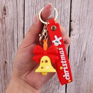 Detail of a Christmas keychain featuring a red wrist strap, yellow star bell, and golden hook