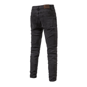 Detail of slim-fit dark denim jeans showing back pockets and premium leather logo patch