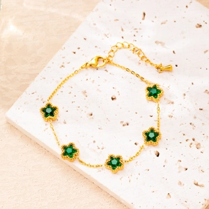 Macro detail of 18K gold-plated bracelet with five leaf flowers and green stones