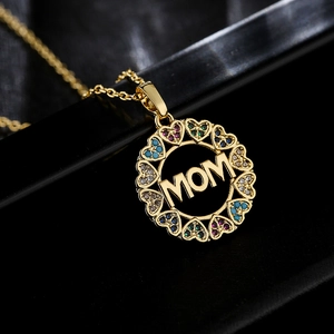Gold plated MOM heart necklace with colorful zircons on a dark reflective surface