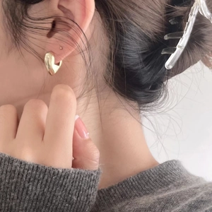 Polished gold heart studs in 925 sterling silver worn by a model for a modern look