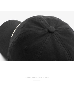 Macro detail of black cotton baseball cap showing top button and twill fabric texture