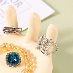 Hand-shaped resin jewelry tray displaying silver vintage rings and beaded bracelets