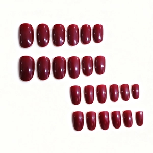 Faux ongles courts ovales rouge cerise brillant de tailles variées sur fond blanc
