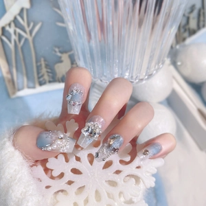 Detailed view of blue gradient coffin nails with silver glitter, rhinestones and snowflakes