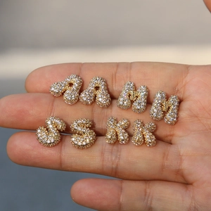 Pave-set zircon 18k gold-plated alphabet stud earrings A M S K held in hand