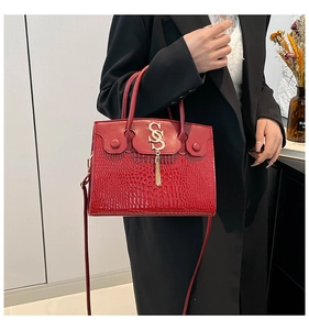 Détail du sac à main rouge effet crocodile avec boucle dorée et pampille élégante