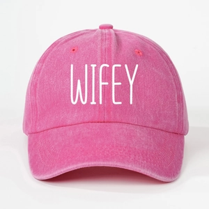 Detailed close-up of the WIFEY printed logo on a washed fuchsia cotton baseball cap
