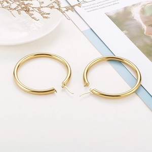 Detailed macro view of large chunky 18K gold plated hollow hoop earrings on a tray