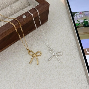 925 silver bow necklace with twisted texture in gold and silver on a textured background