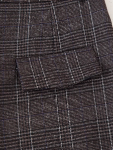 Gros plan sur la texture du tissu à carreaux marron et les coutures de la poche