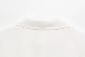Close-up of clean stitching and neckline details on white mixed-fabric blazer dress