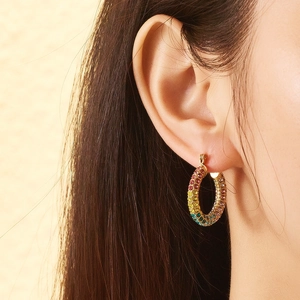 Close-up of 18k gold-plated hoop earring with rainbow zircon inlay on model ear