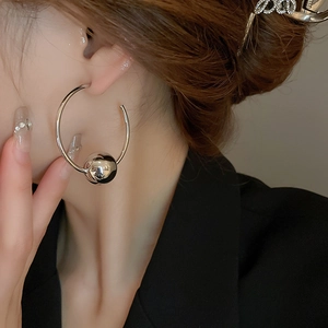 Close-up of minimalist silver circular hoop earring with a sliding polished metal bead detail