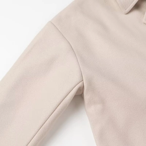 Detailed close-up of apricot wool coat sleeve showing soft texture and stitching