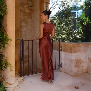 Détail d'une robe de soirée en satin rouge rouille montrant le dos nu et la texture en soie