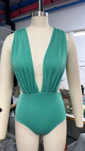 Detail of green shimmering fabric and deep V-neckline on this one-piece swimsuit