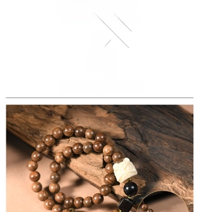 Detailed view of sandalwood beads featuring an intricately carved white Buddha charm