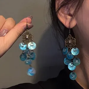 Detail of vintage bronze drop earrings with blue gradient shell tassel sequins