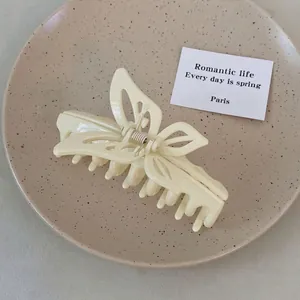 Elegant cream butterfly hair claw clip with hollow design on minimalist ceramic tray