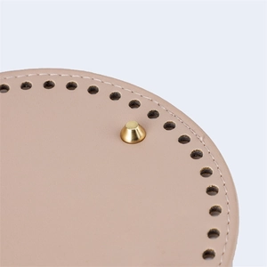 Detailed macro of 15cm round beige PU leather bag base with pre-punched holes and gold stud