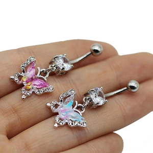 Gros plan de piercings de nombril papillon rose et bleu tenus par des doigts pour la taille
