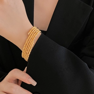 Macro shot of multi-layer gold plated bracelet with textured finish on a dark sleeve