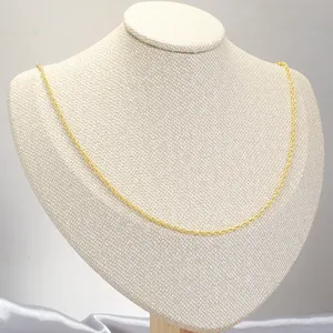 Detail shot of golden water wave chain necklace on a beige display neck mannequin