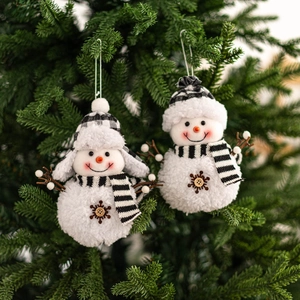 Detail of plush snowman ornaments with plaid scarves hanging on green Christmas tree branches