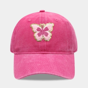 Détail d'une casquette en coton délavé rose avec broderie papillon et paillettes dorées