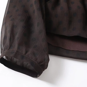 Detailansicht der dunkelbraunen Polka-Dot-Chiffonbluse mit Manschetten und Saumnähten