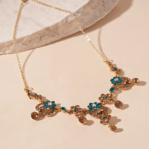 Vintage gold chain necklace featuring floral patterns and blue champagne crystals