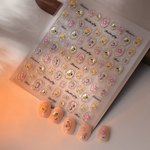 Détail de stickers pour ongles floraux avec motifs abeilles et papillons en relief doré