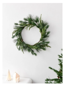 Close-up of a 50cm Nordic green pine needle Christmas wreath on a white wall