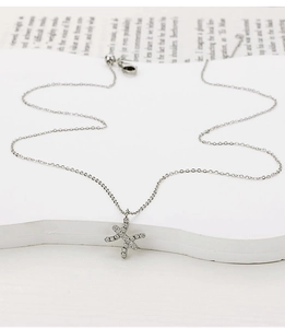 Macro detail of silver X-shaped pendant with cubic zirconia and delicate steel chain