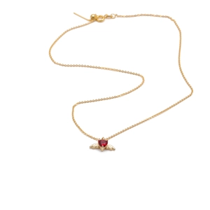 Detail of gold-plated wing pendant necklace with a red heart-shaped gemstone