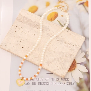 Multicolor pearl necklace with a pink heart pendant on a natural stone background