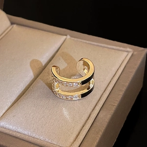 Detail of a gold double-layer C-shaped ear cuff with black enamel and zircons in a box