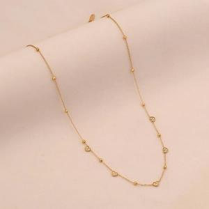 Close-up of gold stainless steel necklace featuring small beads and heart-shaped pendants