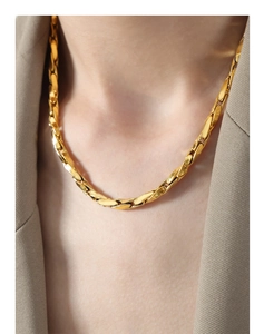Close-up of a polished gold-plated geometric interlocking chain necklace worn by a model