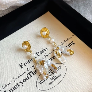 Macro shot of baroque pearl earrings with gold leaf and vintage embossed metal studs