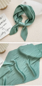 Macro detail of sage green pleated scarf showing fine accordion pleats and soft texture