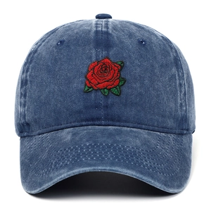Vista frontal de gorra de béisbol azul lavada con bordado de rosa roja sobre fondo blanco