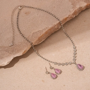 Detailed macro of pear-shaped pink gemstone jewelry set on natural stone background