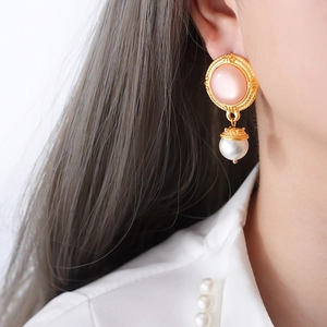 Elegant gold-plated titanium earrings with pink zircon and pearl charms on a model