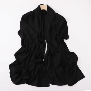 Detailed view of black solid color silk-like scarf with soft texture draped on wood hanger