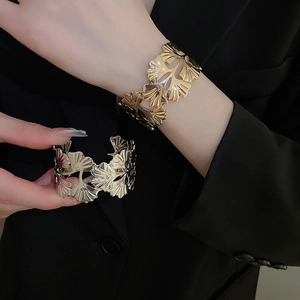 Detailed view of hollow ginkgo leaf cuff bracelets in polished gold and silver finishes