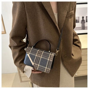 Detail of a retro plaid handbag with gold metal bar and adjustable leather shoulder strap