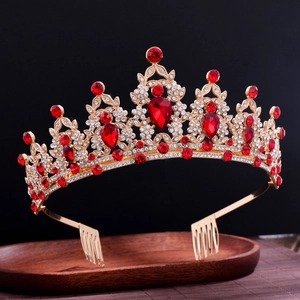 Luxurious baroque gold bridal crown with red rhinestones on a rustic wooden tray